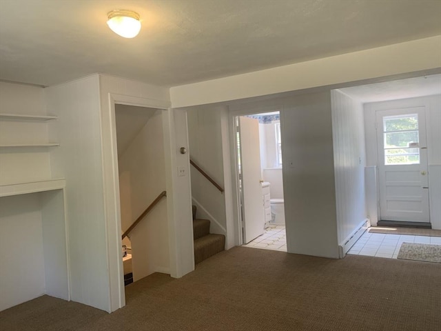 foyer entrance with light tile patterned floors, stairs, and light colored carpet