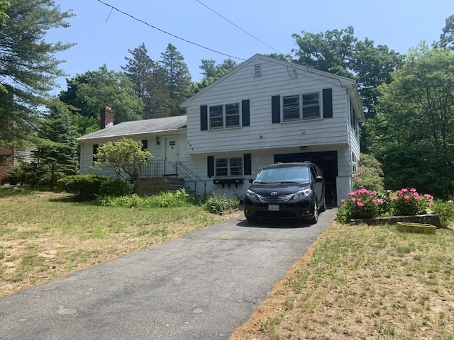 tri-level home with a front yard, driveway, and a garage