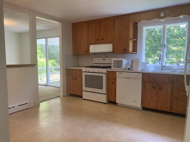 kitchen with plenty of natural light, brown cabinets, a baseboard heating unit, and white appliances