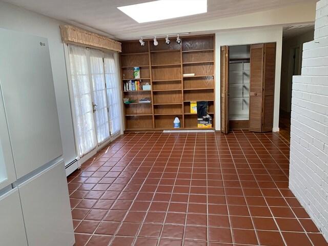 interior space with rail lighting, brick wall, and a baseboard radiator