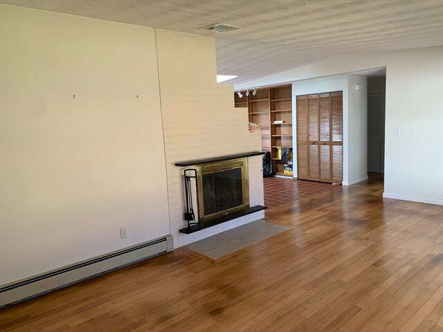 unfurnished living room featuring a textured ceiling, wood-type flooring, and baseboard heating