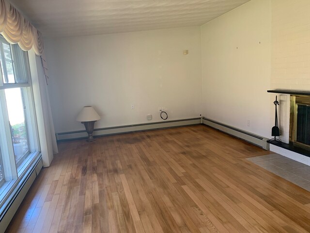 unfurnished living room with a baseboard radiator and hardwood / wood-style flooring