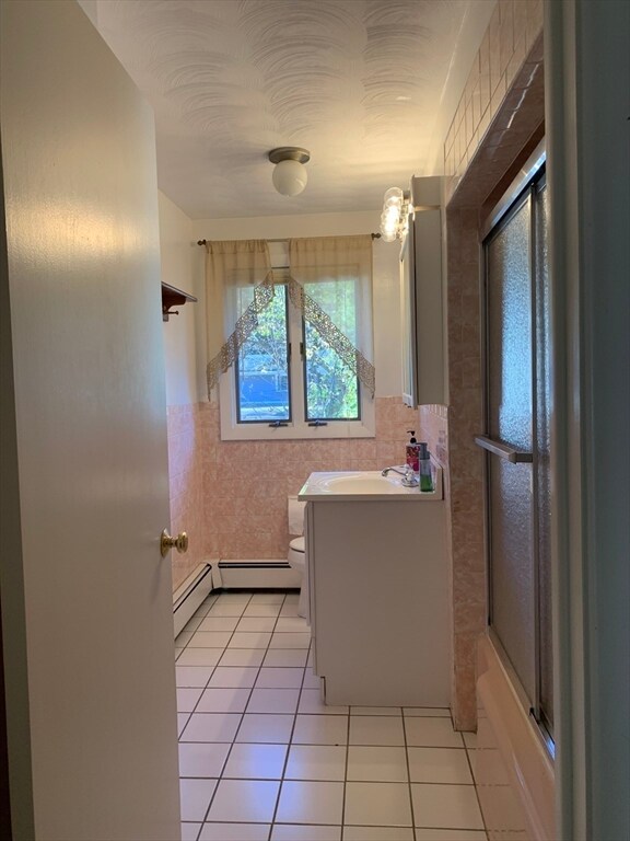 full bathroom with vanity, tile patterned floors, bath / shower combo with glass door, toilet, and tile walls