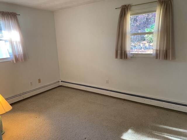 spare room with carpet flooring, baseboard heating, and plenty of natural light