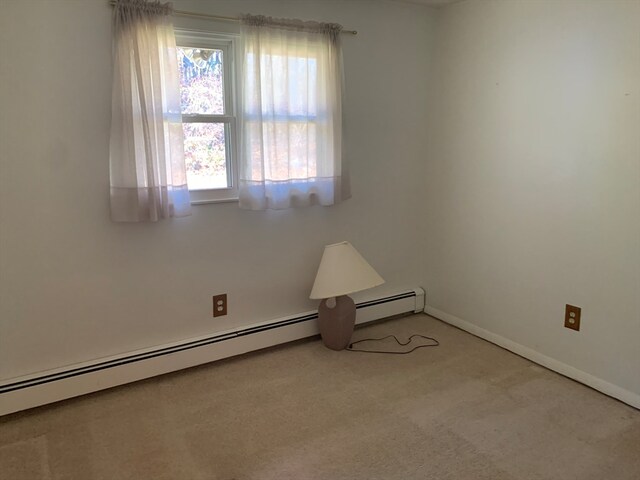 unfurnished room featuring baseboard heating and light carpet