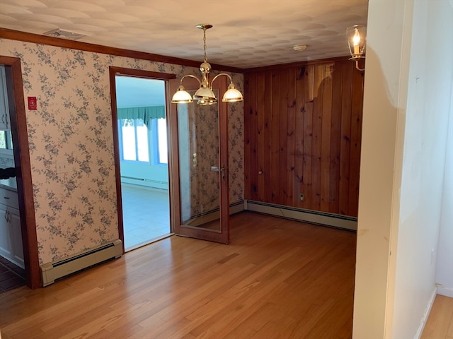 unfurnished dining area featuring a chandelier, ornamental molding, light hardwood / wood-style floors, and a baseboard heating unit