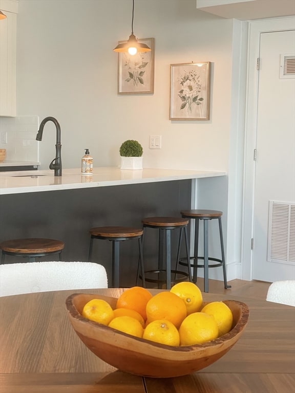 interior space featuring backsplash, sink, and hanging light fixtures