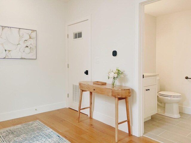 kitchen with sink, light wood-type flooring, appliances with stainless steel finishes, hanging light fixtures, and white cabinets