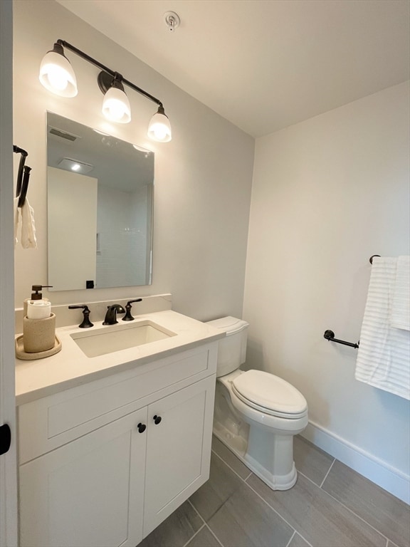 bathroom with toilet, vanity, and tile patterned floors