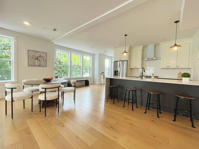 kitchen featuring wall chimney range hood, decorative backsplash, stainless steel gas range oven, and white cabinets