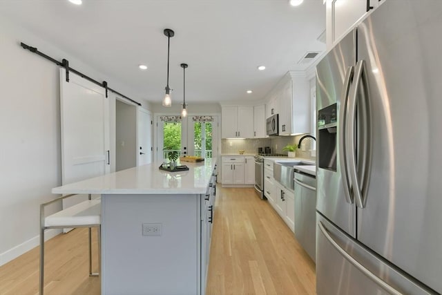 176 Medford St Unit 176, Arlington, MA 02474 - kitchen with stainless steel appliances, a barn door, a center island, light countertops, and a breakfast bar