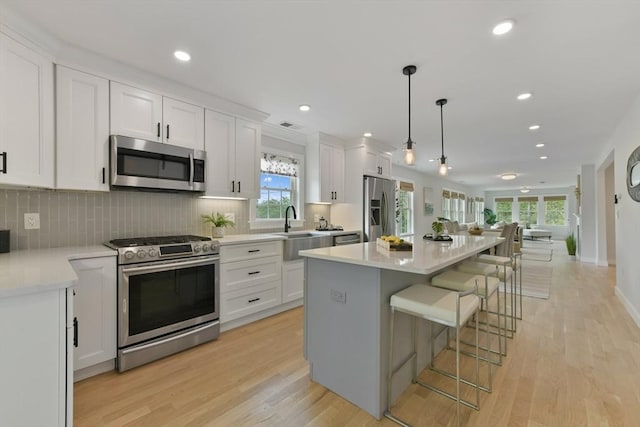 176 Medford St Unit 176, Arlington, MA 02474 - kitchen featuring stainless steel appliances, white cabinets, a breakfast bar, plenty of natural light, and recessed lighting