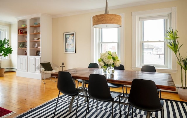 dining space with baseboard heating, crown molding, and light wood finished floors