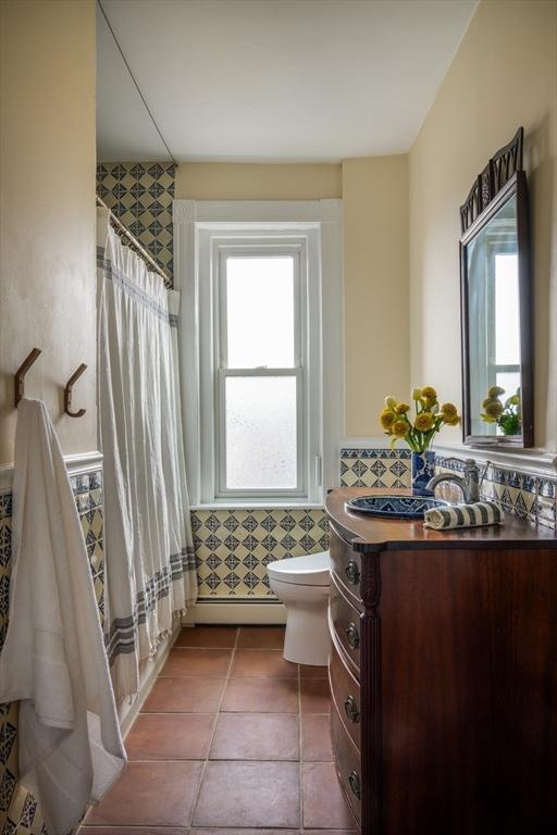 bathroom featuring vanity, a baseboard radiator, tile patterned flooring, curtained shower, and toilet