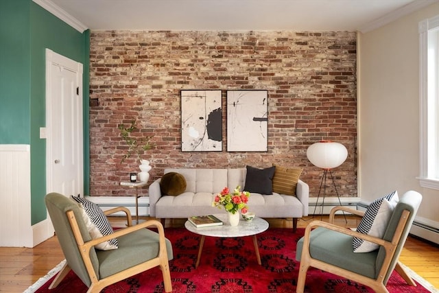 living room with brick wall, crown molding, and wood finished floors