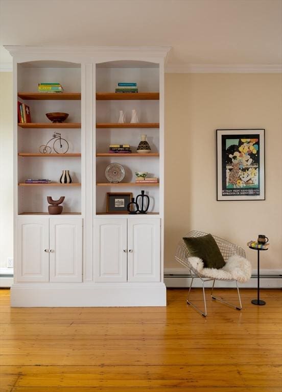 interior space with built in features, a baseboard heating unit, crown molding, and wood finished floors