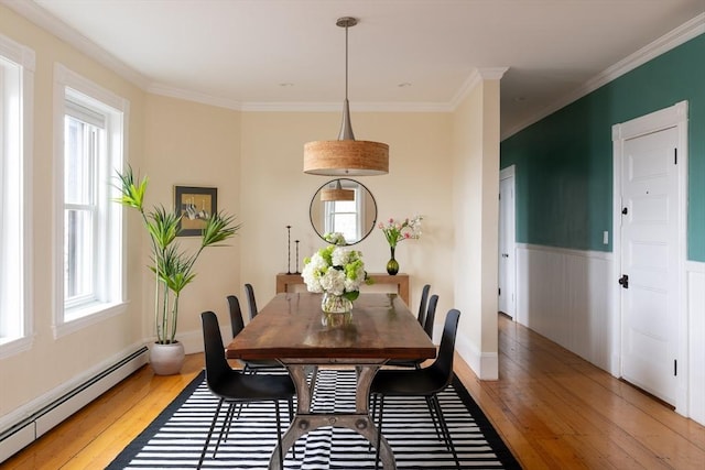 dining space with a baseboard radiator, wainscoting, light wood-style flooring, and crown molding