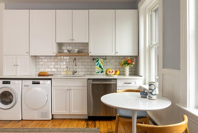 kitchen featuring a sink, washing machine and dryer, white cabinets, light countertops, and dishwasher