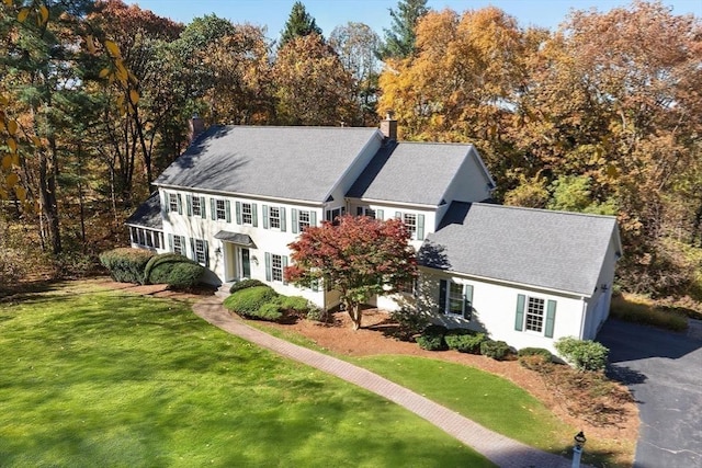 22 Forest Hill Rd, Wayland, MA 01778 - view of front facade featuring a chimney, a front lawn, roof with shingles, and view of scattered trees