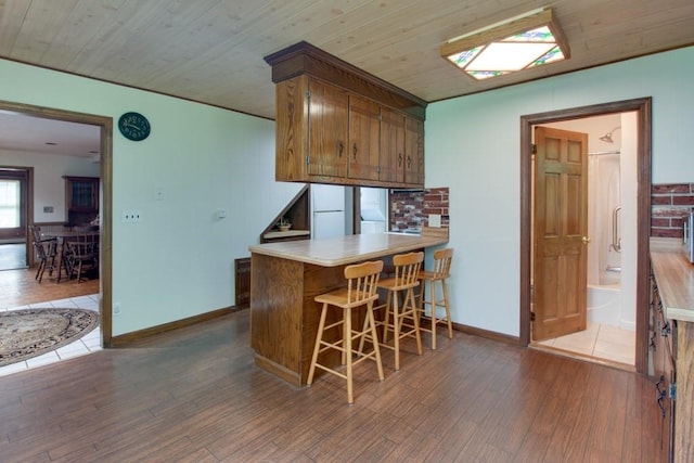 46 Baremeadow St, Methuen, MA 01844 - kitchen with wood finished floors, brown cabinetry, freestanding refrigerator, a breakfast bar area, and light countertops