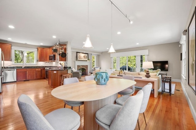 dining space with a brick fireplace, light wood-type flooring, plenty of natural light, and recessed lighting