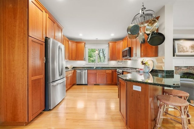kitchen featuring a peninsula, appliances with stainless steel finishes, decorative backsplash, and light wood finished floors