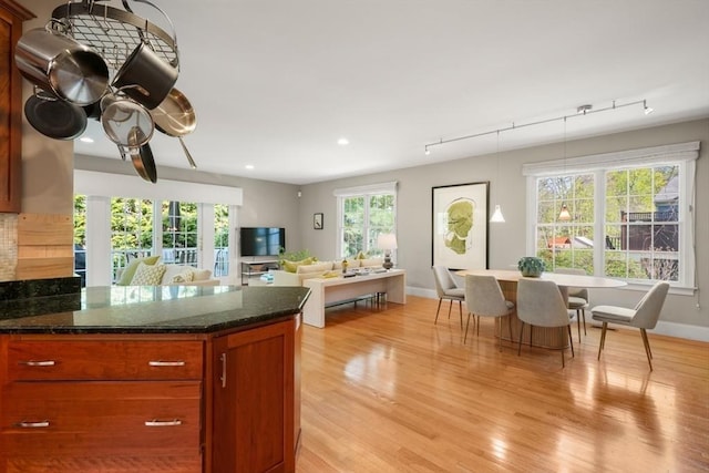 kitchen featuring track lighting, baseboards, dark stone counters, and light wood-style floors