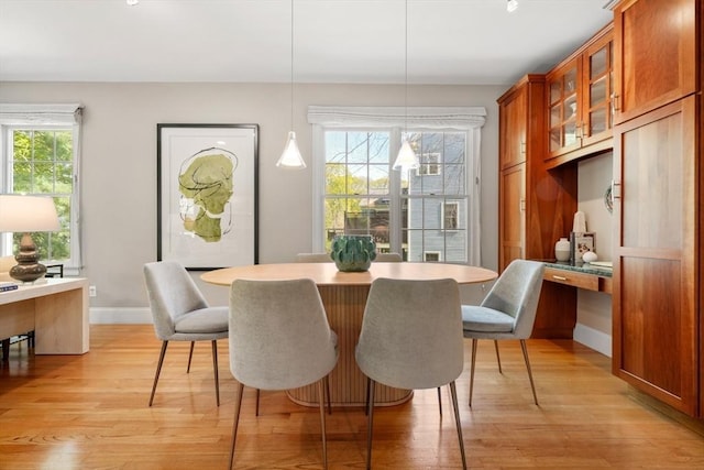 dining area featuring baseboards, built in desk, and light wood-style flooring