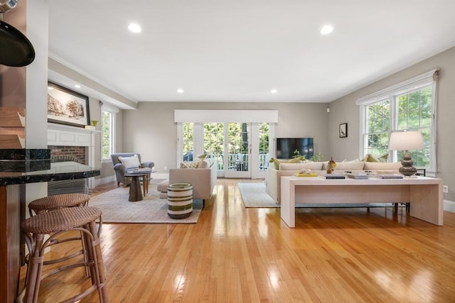 living room with baseboards, light wood-style floors, a fireplace, and recessed lighting