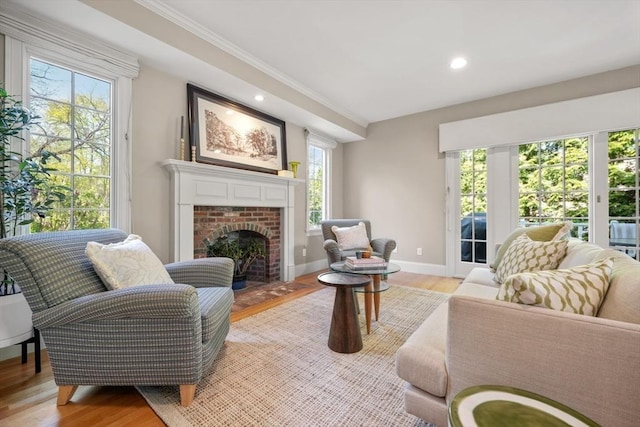 living area with a wealth of natural light, light wood-type flooring, baseboards, and ornamental molding