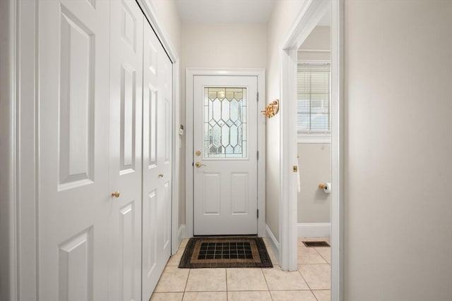 doorway to outside with light tile patterned flooring, baseboards, and visible vents