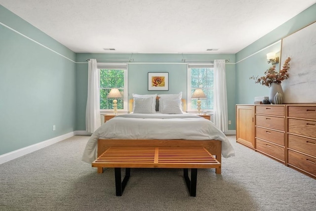 bedroom with multiple windows, light carpet, baseboards, and visible vents