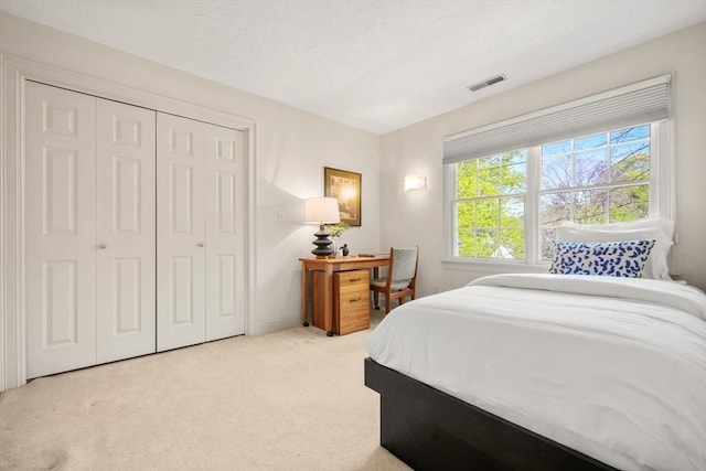 bedroom with light colored carpet, a closet, and visible vents