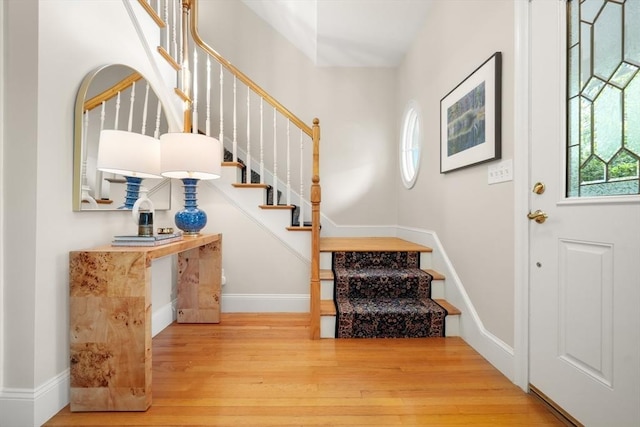 foyer with stairs, a wealth of natural light, baseboards, and wood finished floors
