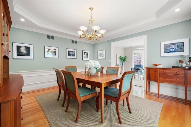 dining room featuring a raised ceiling, ornamental molding, and a chandelier
