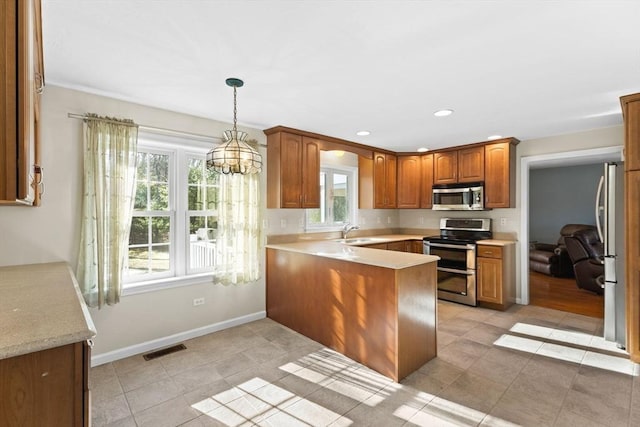 kitchen featuring visible vents, a peninsula, a sink, light countertops, and appliances with stainless steel finishes