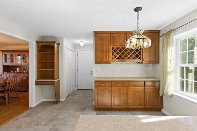 kitchen with brown cabinets, pendant lighting, light countertops, and baseboards