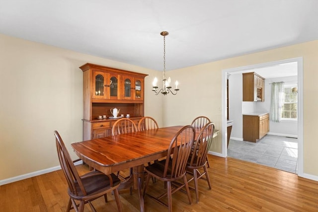 dining area featuring a notable chandelier, baseboards, and light wood-type flooring