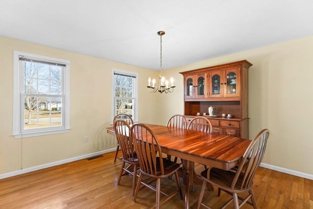 dining area featuring light wood-style floors, visible vents, a wealth of natural light, and a chandelier