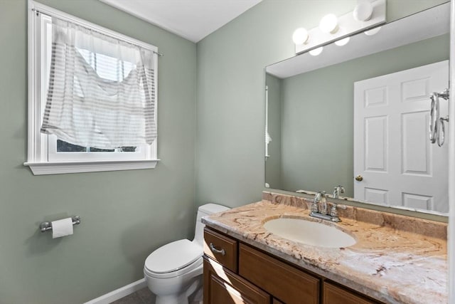 half bathroom with baseboards, toilet, and vanity