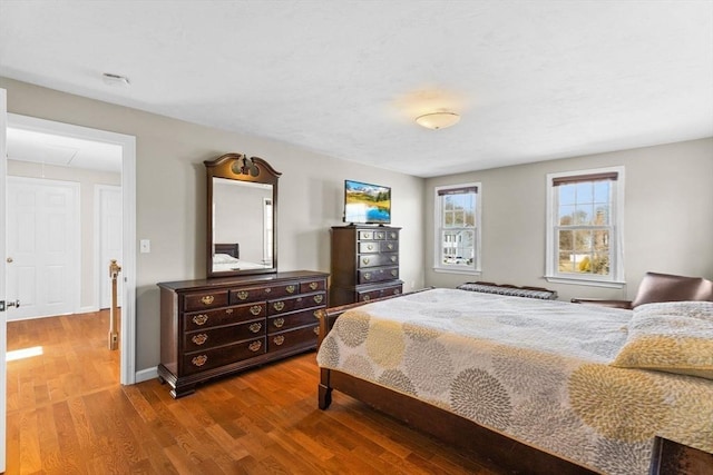 bedroom featuring attic access, baseboards, and wood finished floors