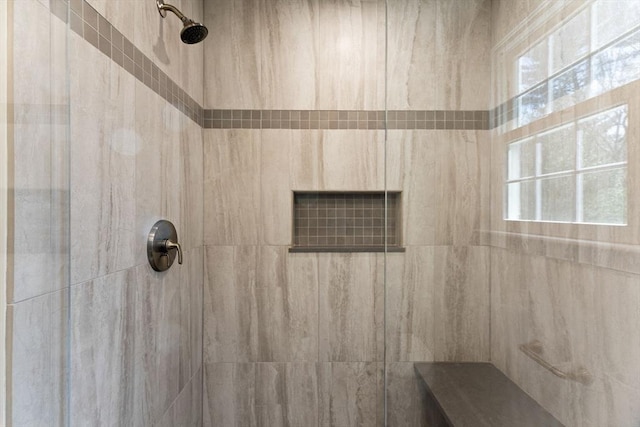 bathroom with a tile shower and a wealth of natural light