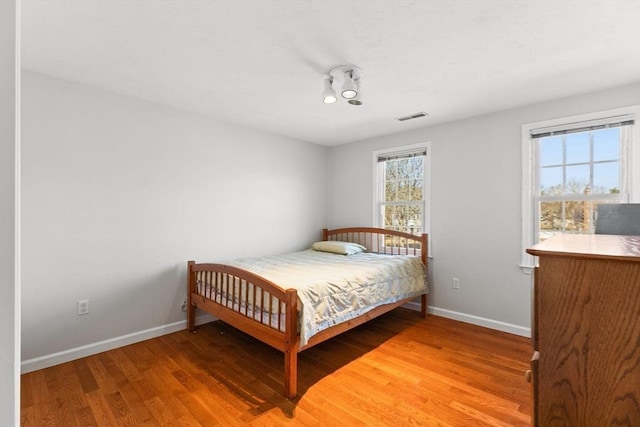 bedroom with baseboards, visible vents, and light wood-type flooring