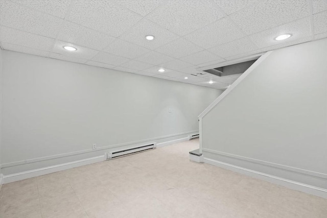 finished below grade area featuring a drop ceiling, recessed lighting, baseboards, and a baseboard radiator