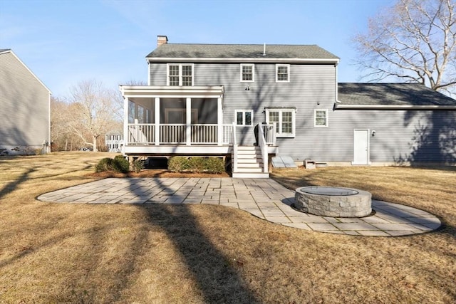 back of house with a fire pit, a chimney, a yard, a sunroom, and a patio area