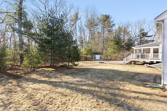 view of yard with an outbuilding, stairs, a storage shed, and a sunroom