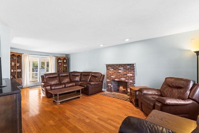 living area featuring a brick fireplace and light wood-style flooring