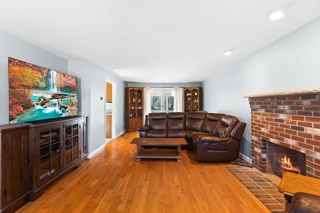 living room with a fireplace, baseboards, and wood finished floors