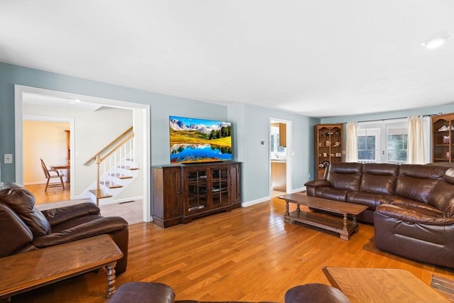 living room with visible vents, stairway, wood finished floors, and baseboards