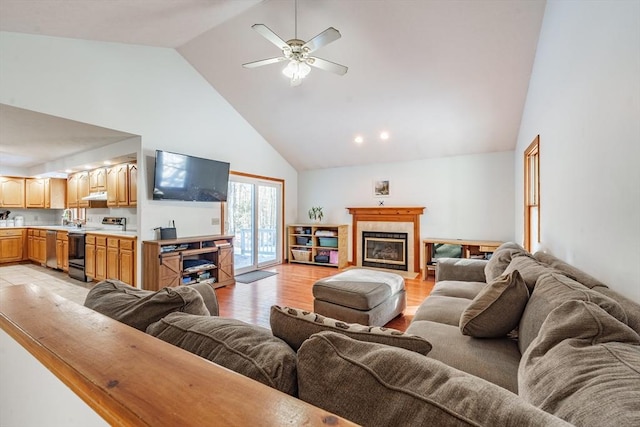 living room with a tiled fireplace, ceiling fan, high vaulted ceiling, and light hardwood / wood-style floors